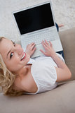 Woman looking up at the camera has a laptop in front of her