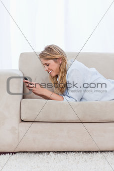 A woman resting on her elbows is texting on her mobile phone