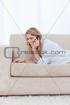 A woman resting on her elbows is talking on her mobile phone