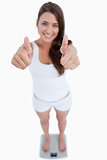 Smiling woman placing her thumbs up while weighing herself
