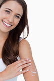 Smiling woman looking at the camera while applying cream on her 