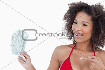 Smiling woman pointing a fan of notes