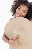 Young woman hiding her body behind a straw hat