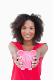Pink piggy bank being held by a brunette woman