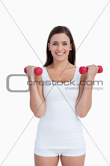 Smiling woman looking at the camera while holding dumbbells