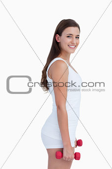 Side view of a smiling woman holding dumbbells