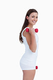 Smiling brunette standing upright while holding weights
