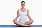 Smiling young woman meditating on a yoga mat