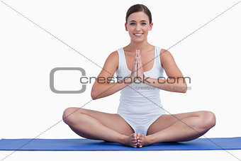 Young woman joining her hands while sitting on a mat