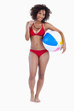 Smiling woman holding a beach ball and sunglasses