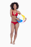 Smiling brunette holding a beach ball while standing upright