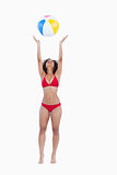 Attractive woman in bikini throwing a beach ball