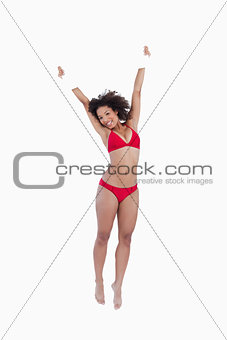 Smiling woman jumping while raising a blank poster above her hea