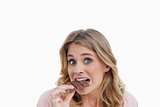 Young blonde woman looking at the camera while eating chocolate