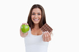 Smiling woman holding a green apple and a piece of chocolate