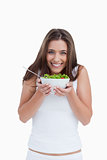 Smiling young woman looking at the camera while holding a bowl o