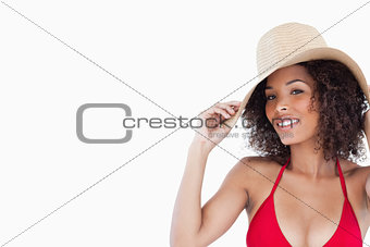 Smiling woman looking at the camera while holding her straw hat