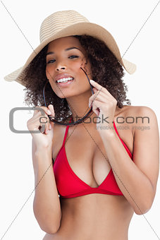 Attractive young brunette holding her sunglasses while wearing a