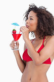 Young brunette looking away while sipping a cocktail