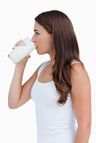 Side view of a young woman drinking a glass of milk