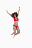 Happy brunette woman jumping while raising her arms