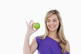 Happy young blonde woman looking at a green apple