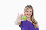 Smiling blonde woman holding a delicious green apple