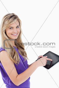 Happy blonde woman looking at the camera while using her tablet 