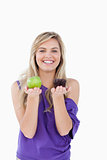 Smiling blonde woman hesitating between a muffin and an apple