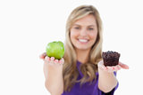 A fruit and a muffin being held by a blonde woman