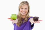 A green apple and a muffin being held by a young woman
