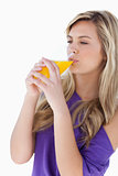 Young blonde woman drinking an orange juice