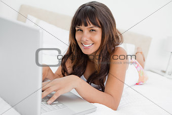 Portrait of a woman in pajama chatting on a laptop