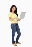 Portrait of a smiling Latin student standing with a laptop