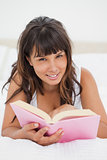 Portrait of a smiling young woman reading a book