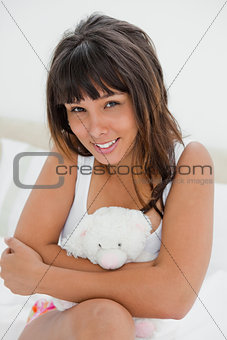 Young woman hugging a small teddy bear