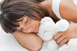 Beautiful young woman sleeping with a teddy bear