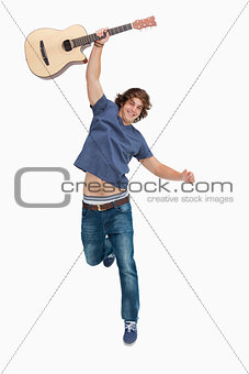 Male student jumping with his guitar