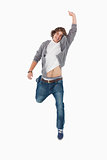 Male student posing by jumping with a raised arm