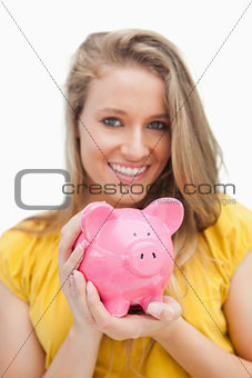 Close-up of a piggy-bank holding by a blond woman