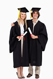 Two students in graduate robe shoulder to shoulder