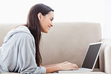 A smiling woman lying on her front using her laptop