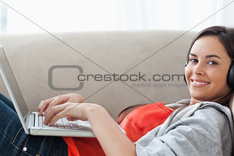 Close up shot of a woman using her laptop and headphones as she 