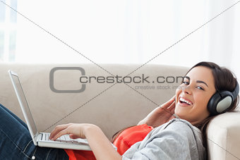 Laughing woman ying on the couch while looking at the camera