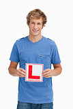Young blond man holding a learner driver sign