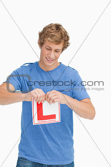 Young man ripping a learner driver sign