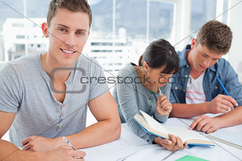 Male student looking at the camera as the other students look at