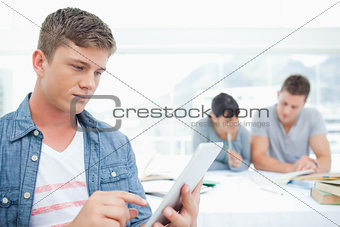 A man with a tablet pc works in front of his friends