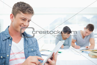 A smiling male using his tablet pc in front of his friends
