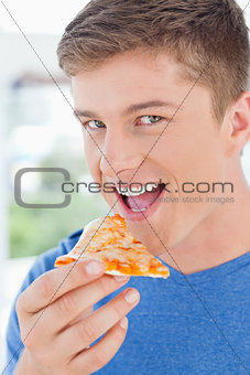 A man with his mouth open about to eat pizza and looking at the 